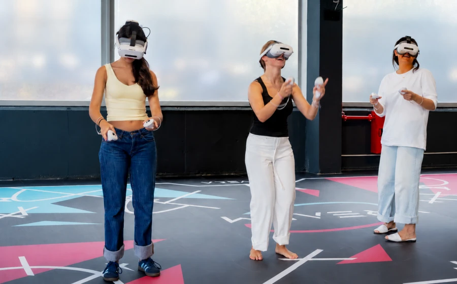 Tres personas jugando con visores y mandos de realidad virtual en la sala de VRealm.